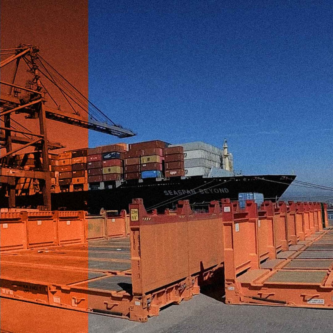 Un gran buque de carga cargado de contenedores está atracado en un puerto, donde se ven en primer plano grúas de color naranja y contenedores apilados.