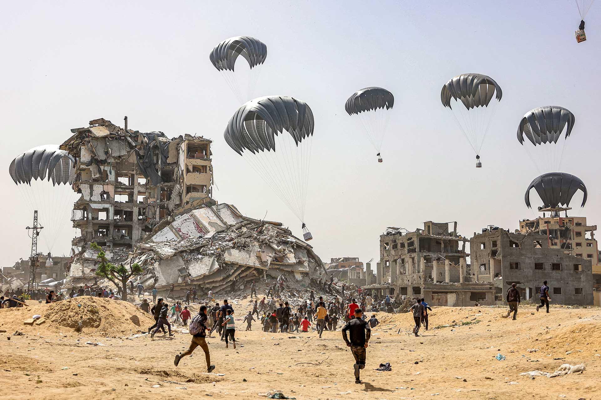 Personas corren para alcanzar los paquetes de ayuda humanitaria en la Franja de Gaza