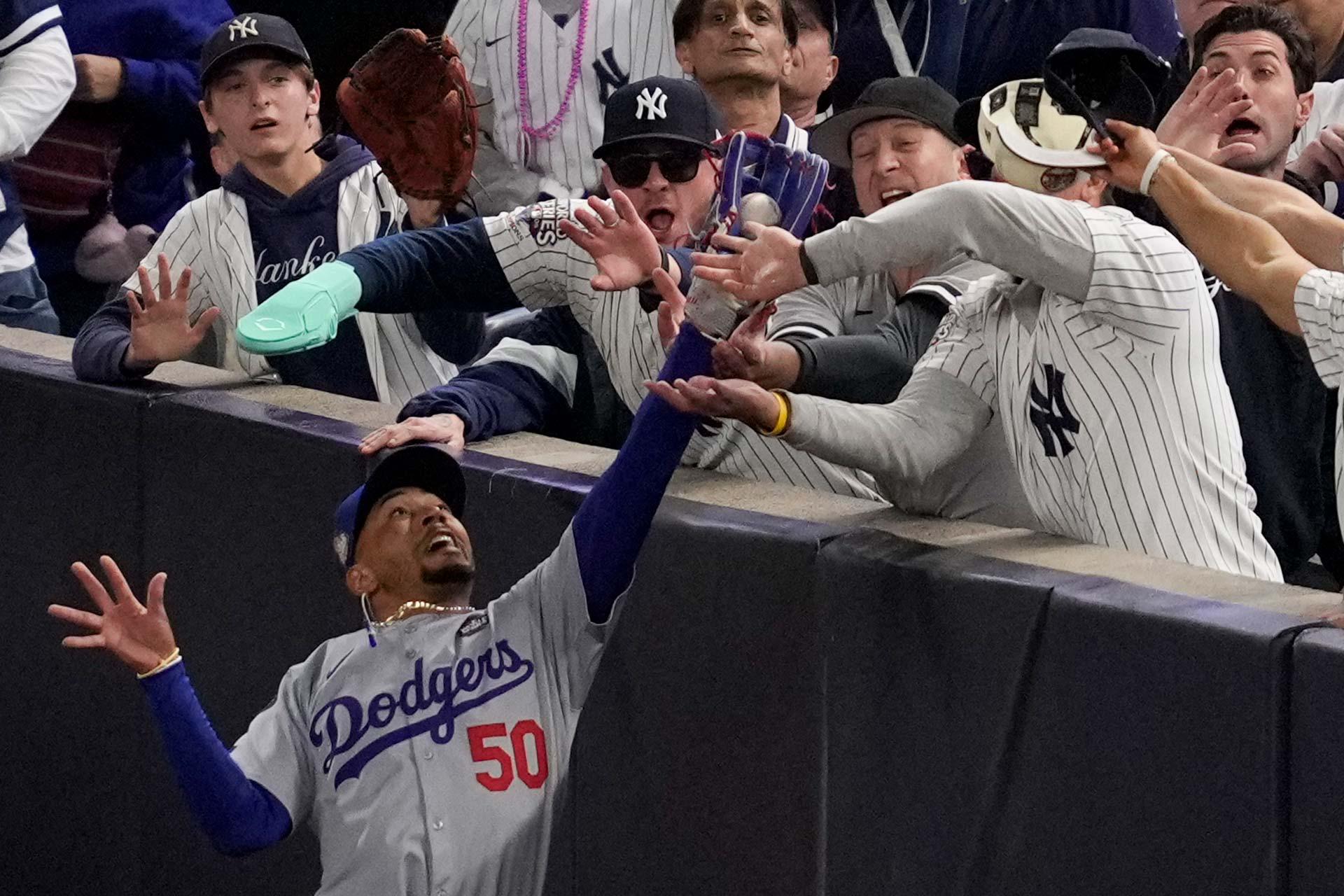 Fans tratan de tomar una pelota atrapada por Mookie Betts de los Dodgers de Los Ángeles durante Serie Mundial de béisbol contra los Yankees de Nueva York