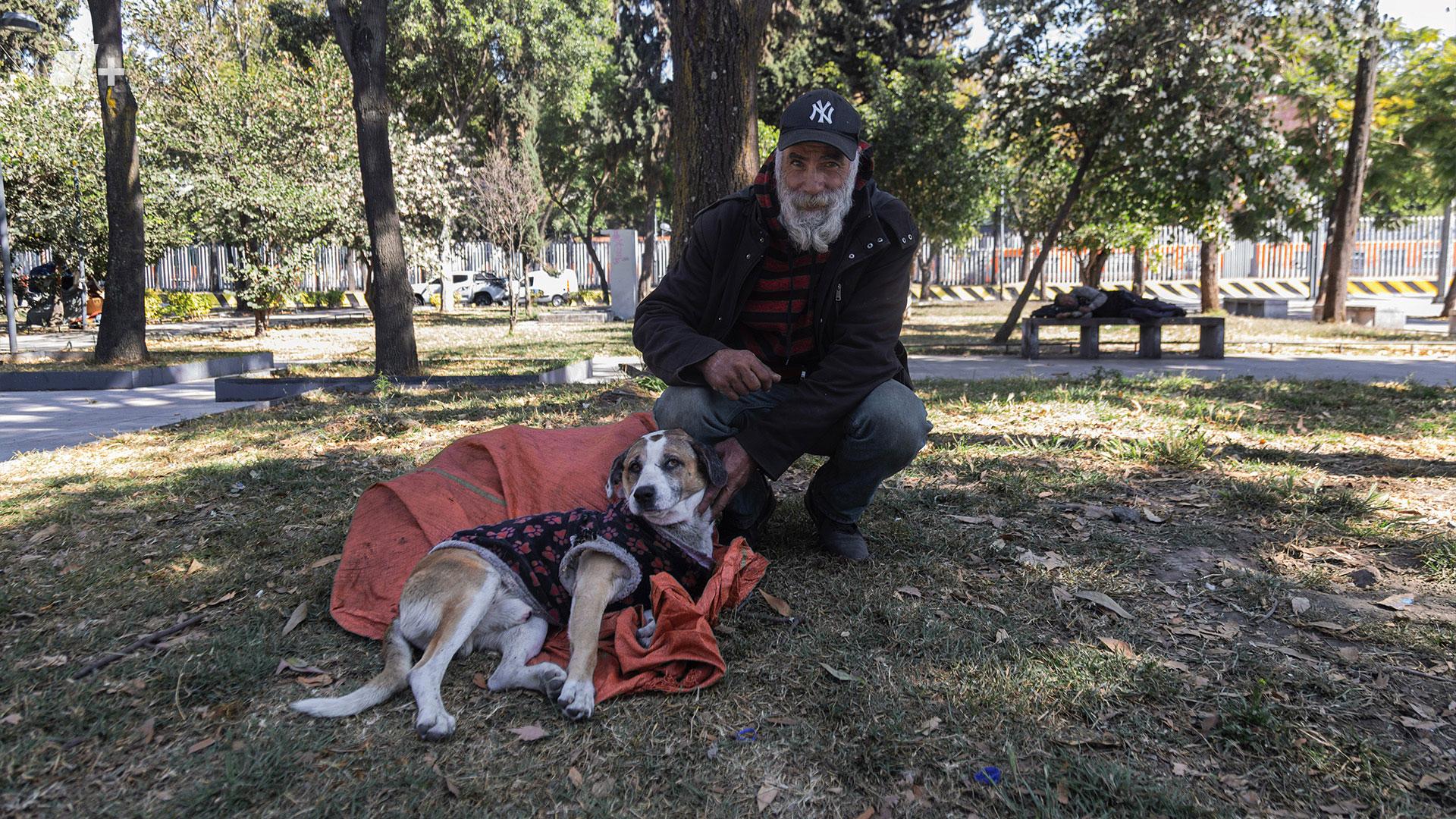 Retrato de un hombre mexicano en situación de calle sentado en un parque junto a su perro
