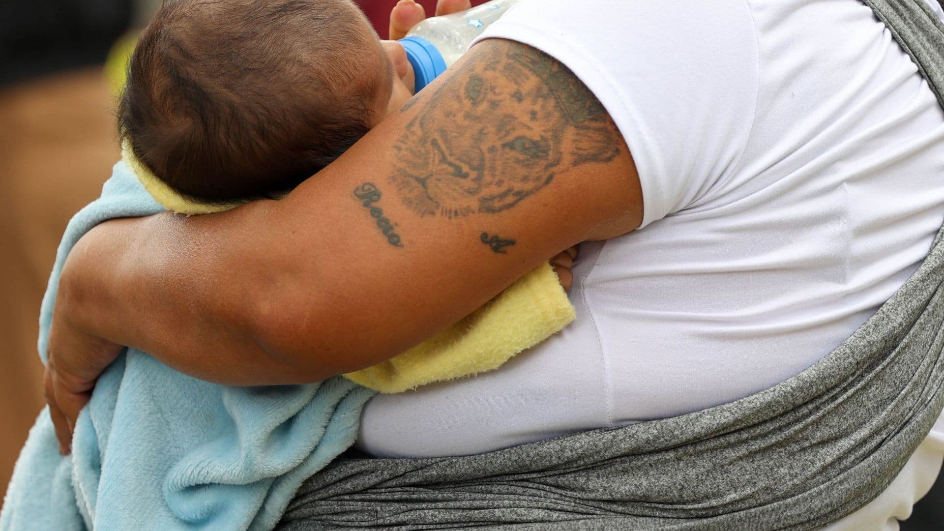 Bebé es sostenido en brazos por sus padres