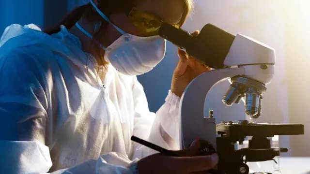 Científica mira por un microscopio