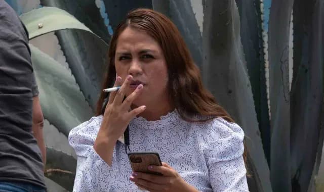 Mujer fumando un cigarro en vía pública