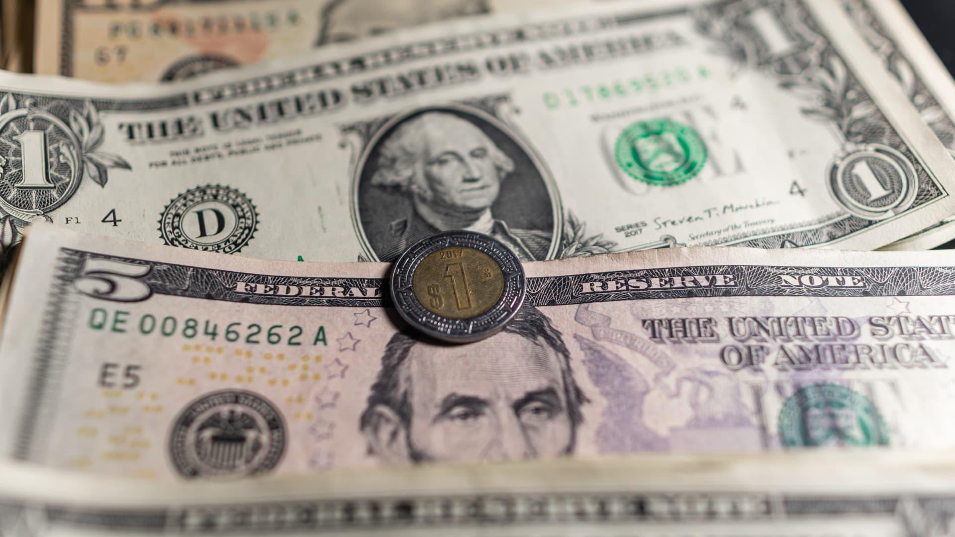 Dólares junto a una moneda de un peso mexicano. Foto: N+