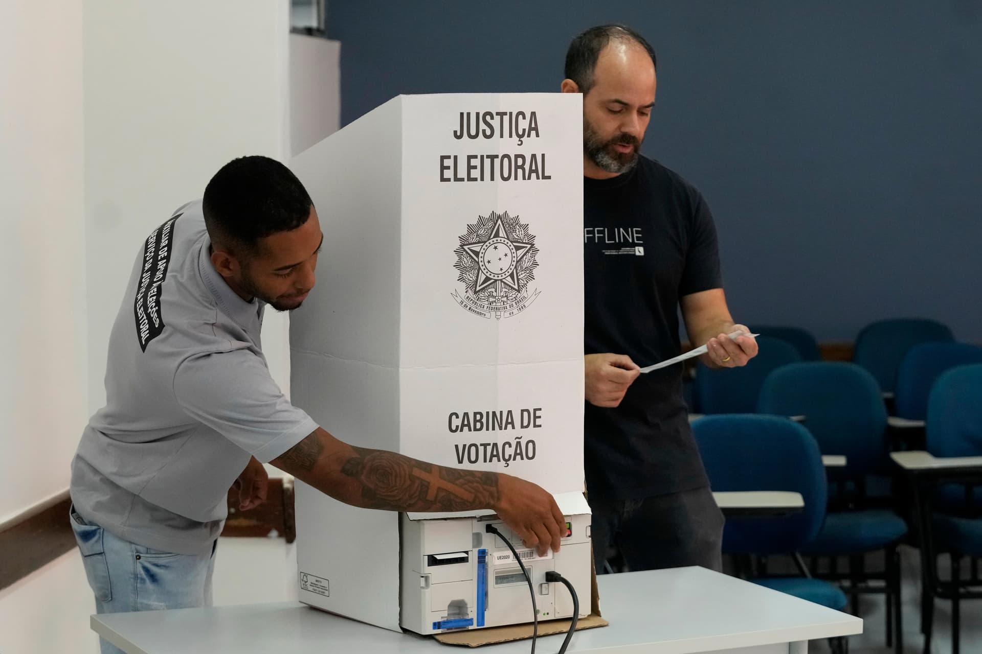 Coordinadores de mesa terminan de instalar una máquina de votación electrónica en un centro de votación.
