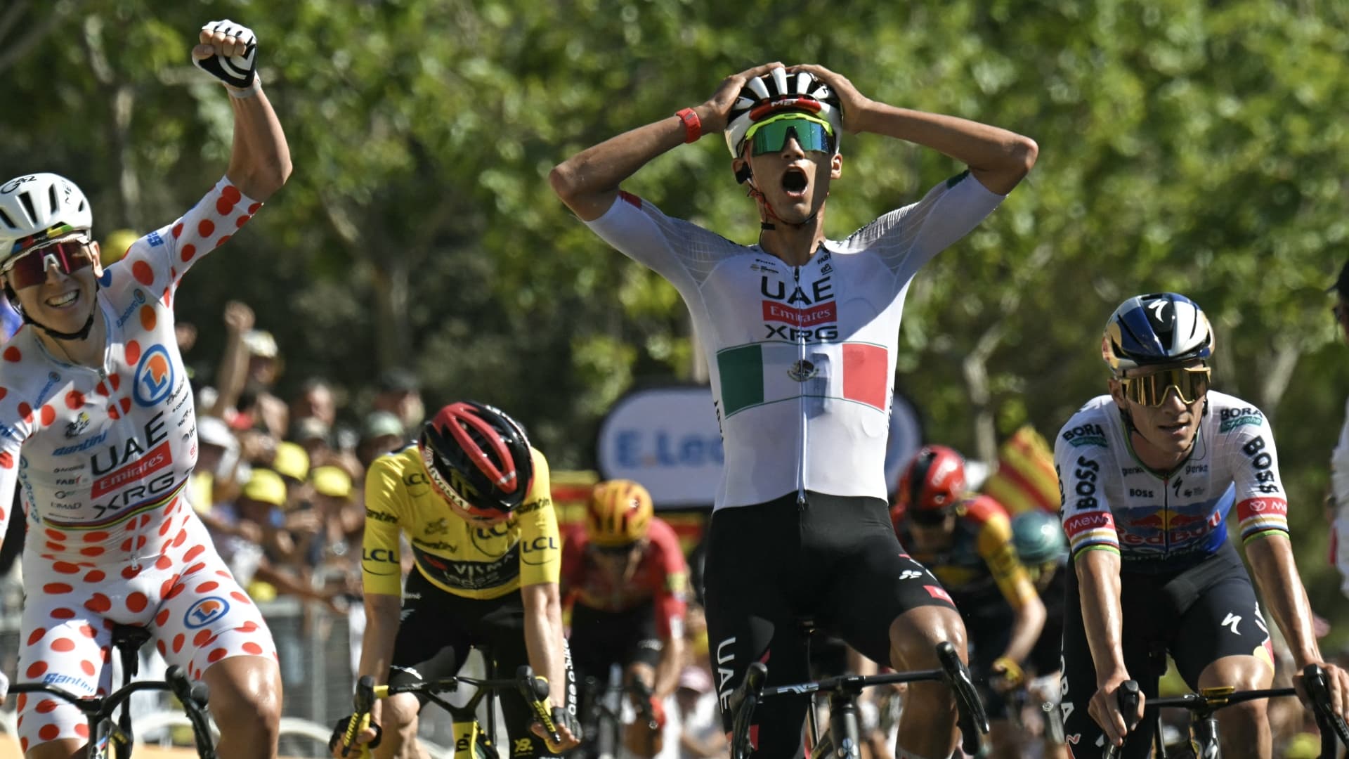 El ciclista mexicano Isaac Del Toro (C), del equipo UAE Team Emirates - XRG, llega a la meta para ganar la segunda etapa por delante del ciclista esloveno Tadej Pogacar (I). Foto AFP