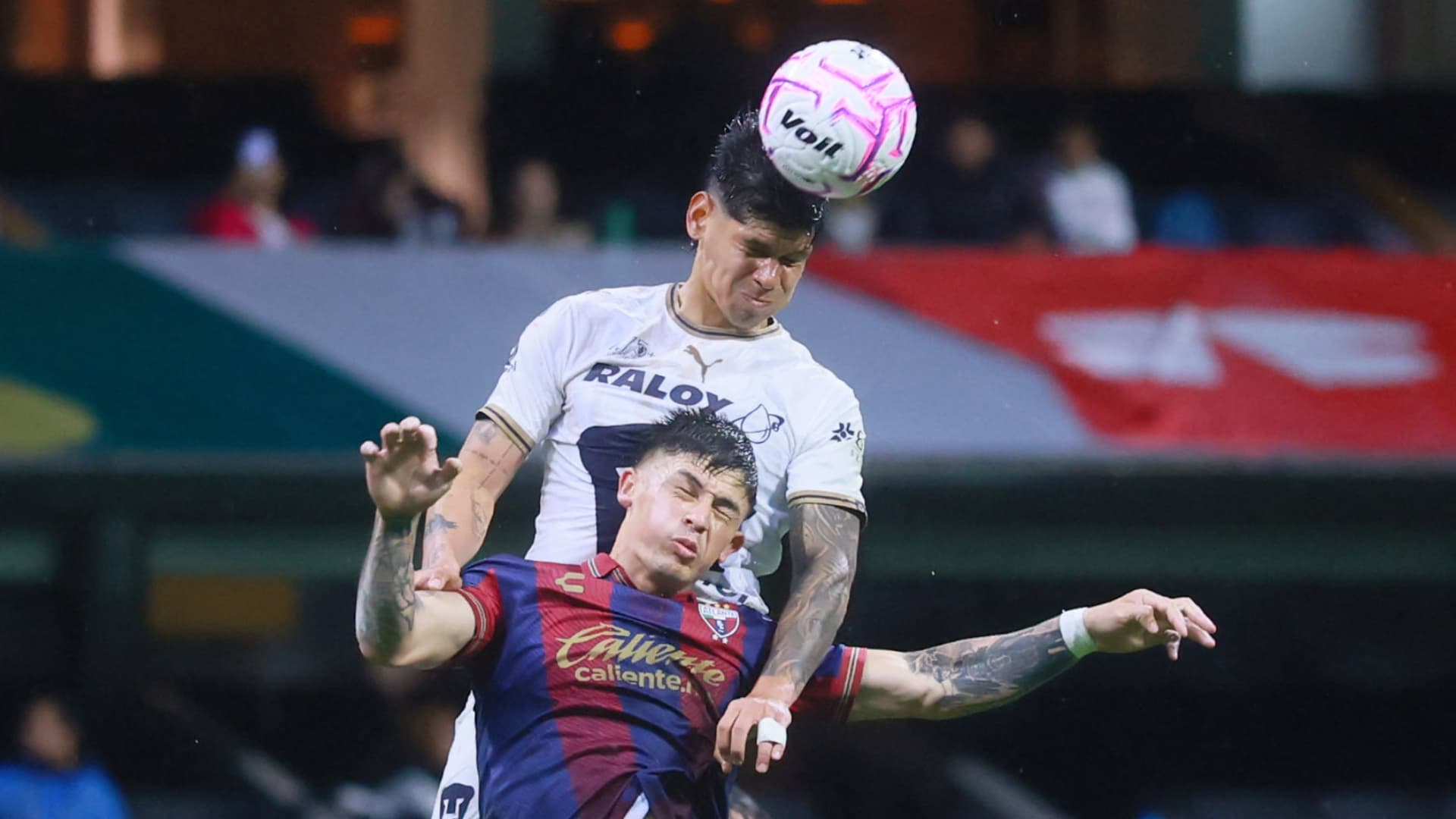 Robert Morales, delantero de Pumas, cabecea la pelota por encima de un zaguero del Atlante