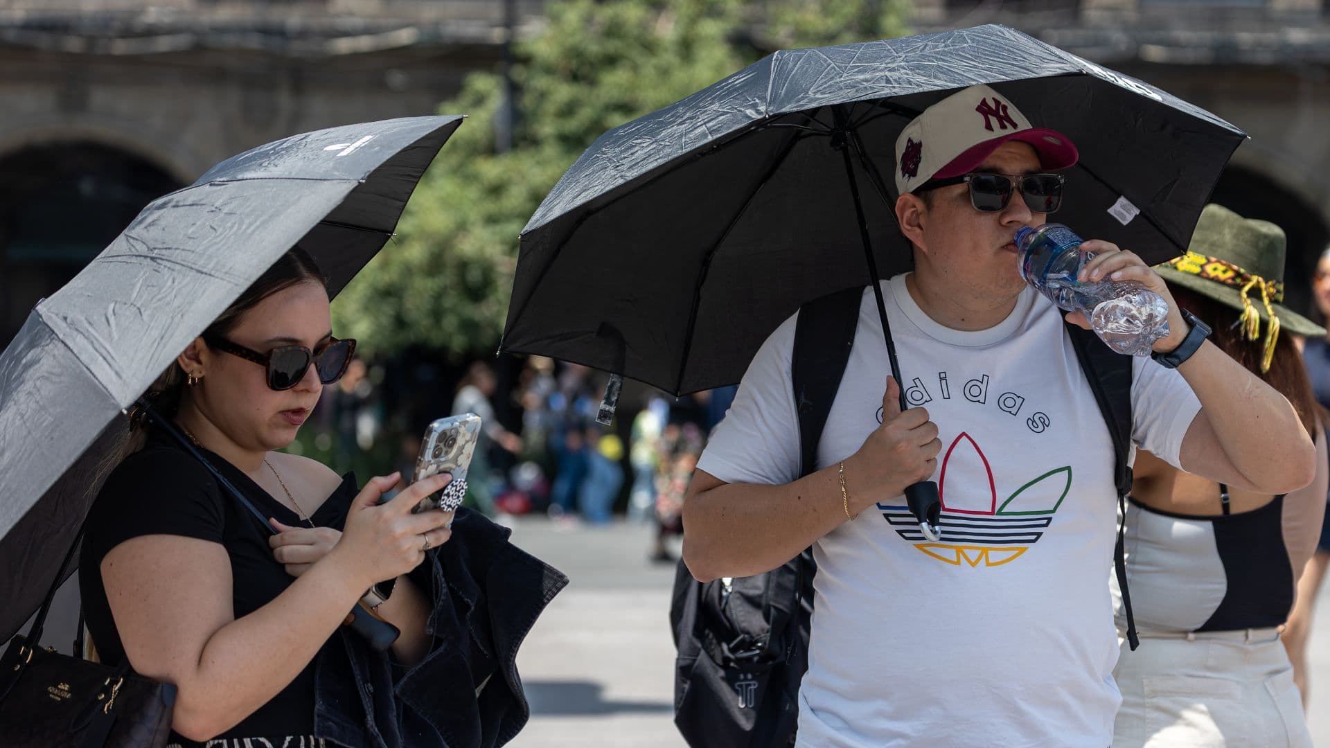 Personas con sombrilla por ola de calor en CDMX