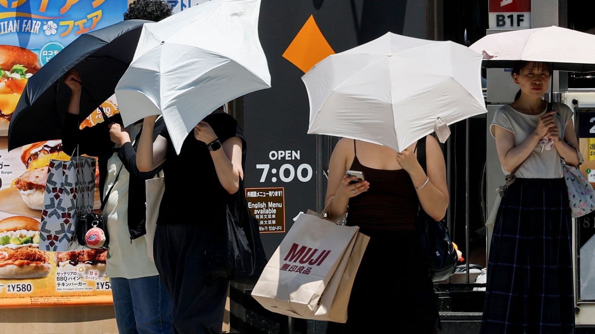 Japoneses usan sombrillas para protegerse del sol