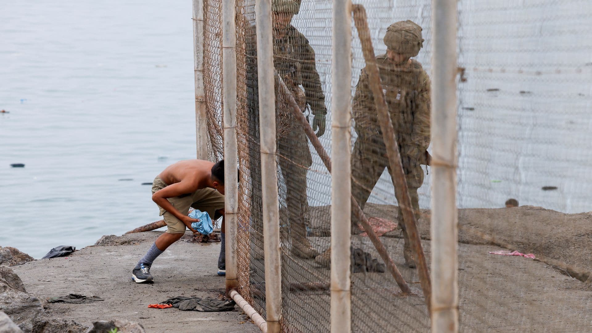 Un joven regresa a Marruecos, atravesando una valla junto a militares de España, el 31 de julio 2026.