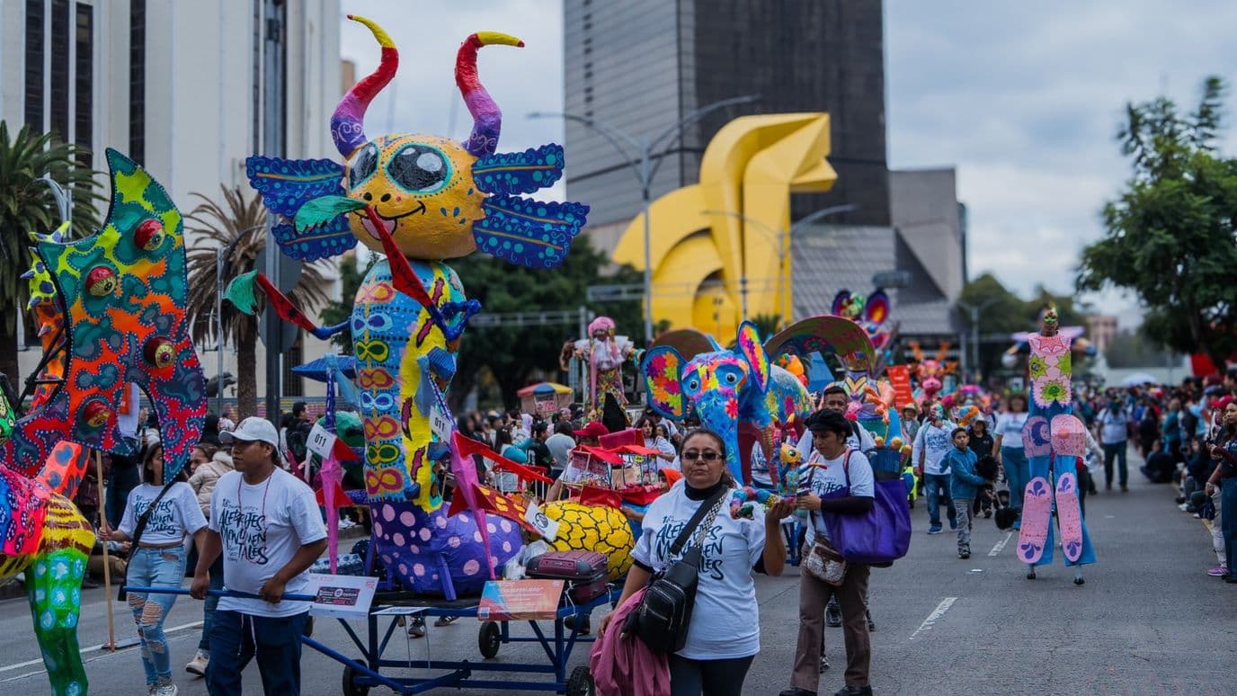 El alebrije "El Alebrijero" avanza sobre una carreta entre asistentes y zancudos durante el desfile. Foto: N+