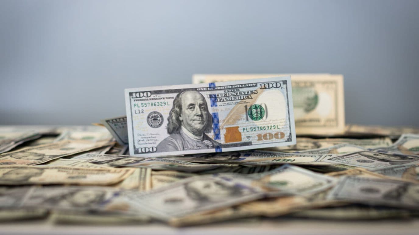 Un billete de 100 dólares sobre una cama de más billetes