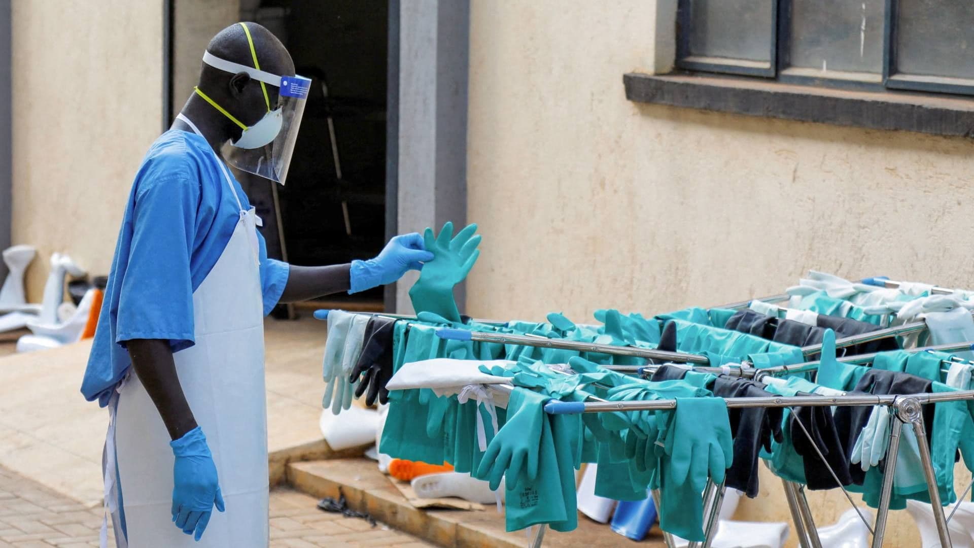 Trabajador ugandés recoge un guante durante la visita del director general de la OMS, Tedros Adhanom Ghebreyesus, a una Unidad de Aislamiento. Foto: Reuters