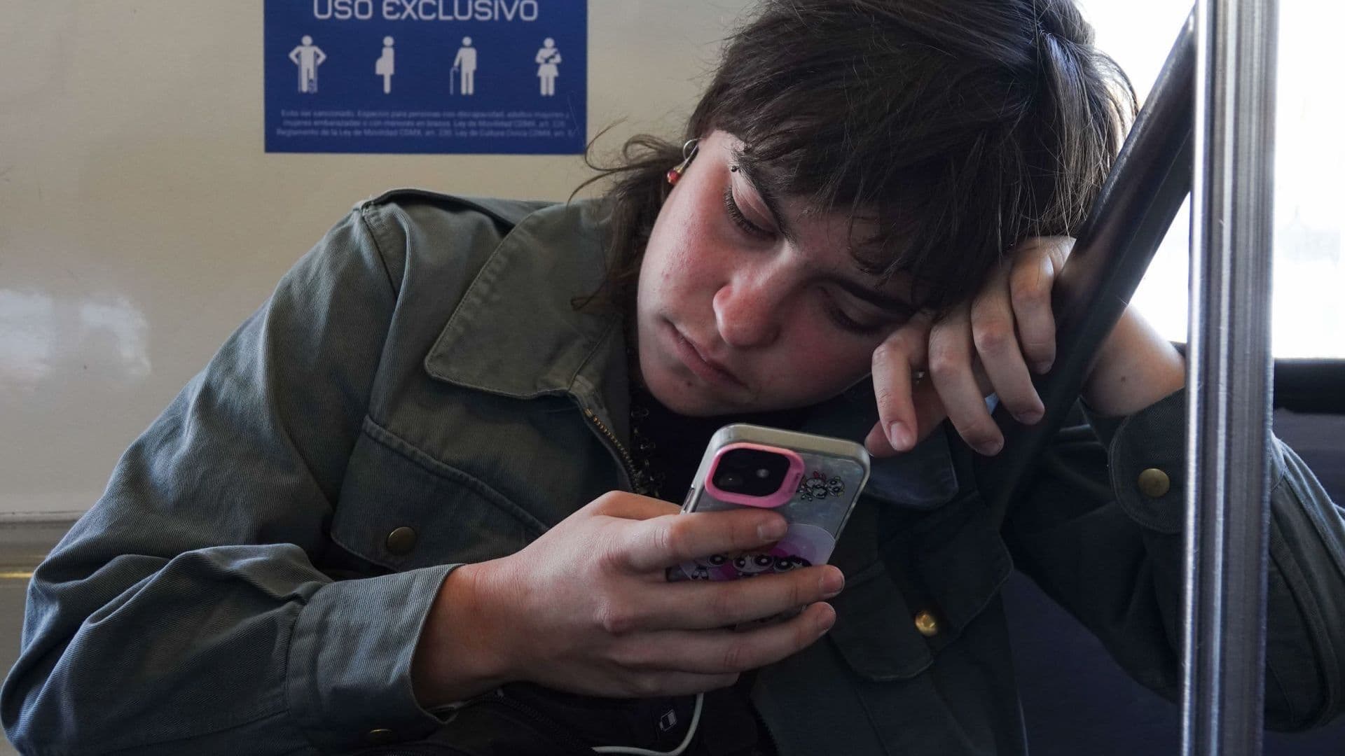 Mujer ve la pantalla de su celular con expresión de cansancio