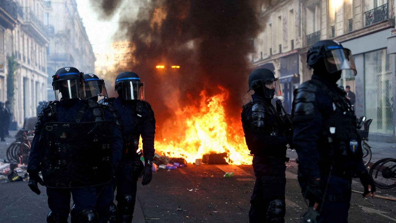 Incendio arde mientras agentes montan guardia durante disturbios civiles, al día siguiente de manifestaciones en París, el 18 de octubre de 2026. Foto: Reuters