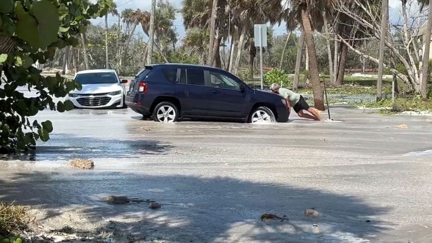 Un hombre intenta sacar su auto de una inundación antes de la llegada de Isaias a Englewood, Florida