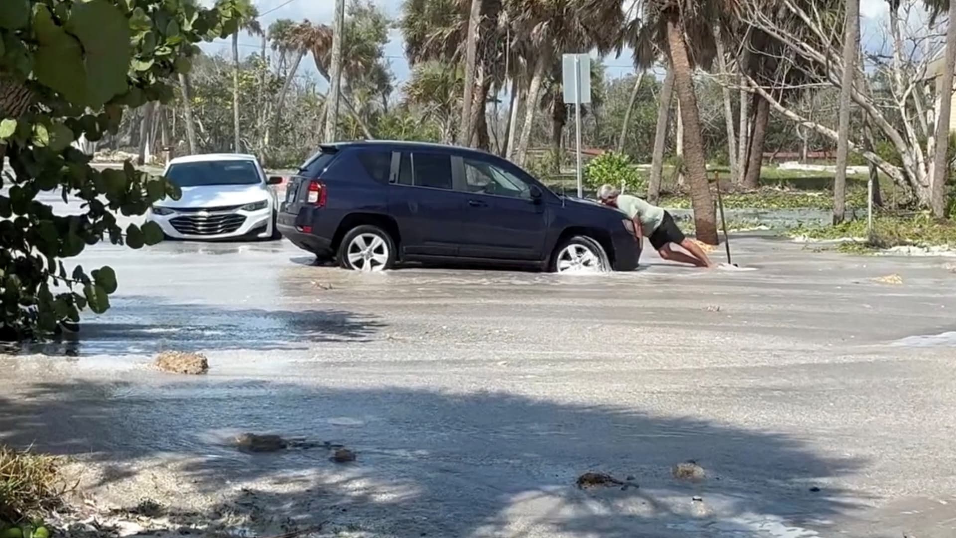 Un hombre intenta sacar su auto de una inundación antes de la llegada de Isaias a Englewood, Florida
