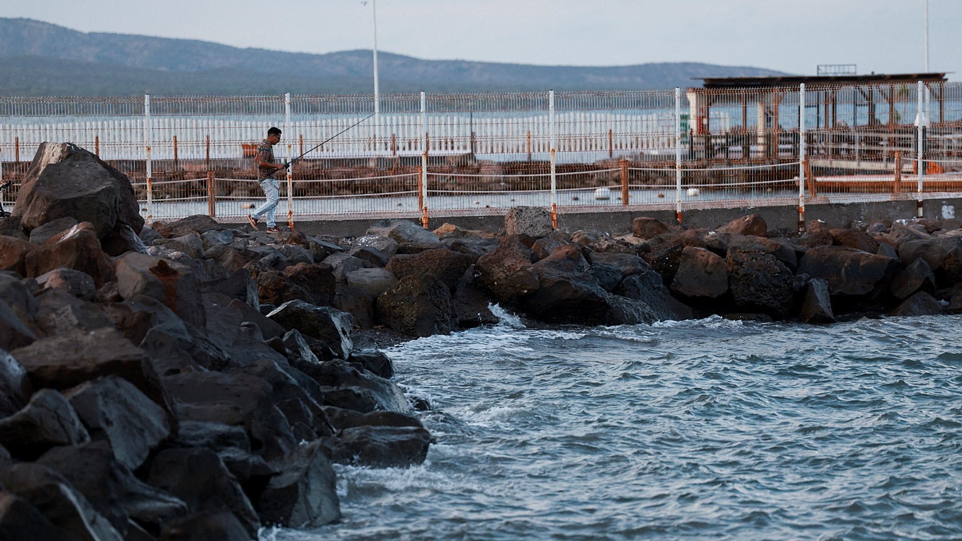 Un hombre camina con una caña de pescar mientras el huracán Polo se acerca a Baja California Sur, el 27 de septiembre de 2026. Foto: Reuters