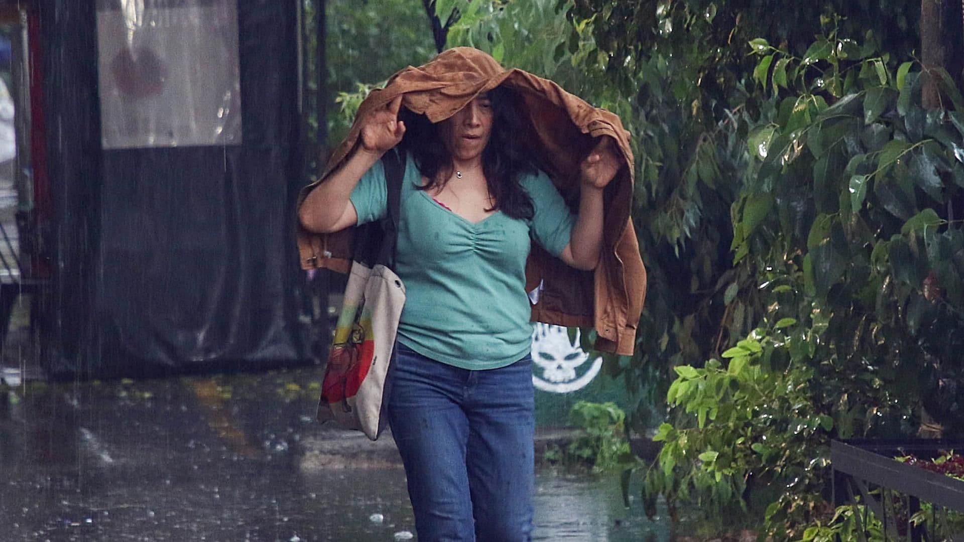 Mujer se cubre la cabeza con una chamarra ante fuerte lluvia con granizo el 22 de junio 2026 en CDMX. Foto: Cuartoscuro | Archivo