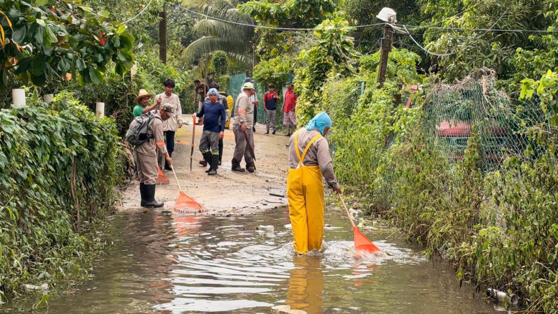 Un grupo de personas realizan limpieza en una calle inundada