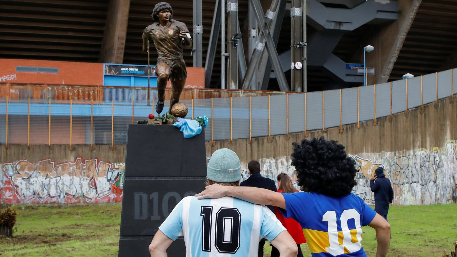 Seguidores de Maradona observan una estatua frente al estadio en Nápoles, Italia. Foto: Reuters