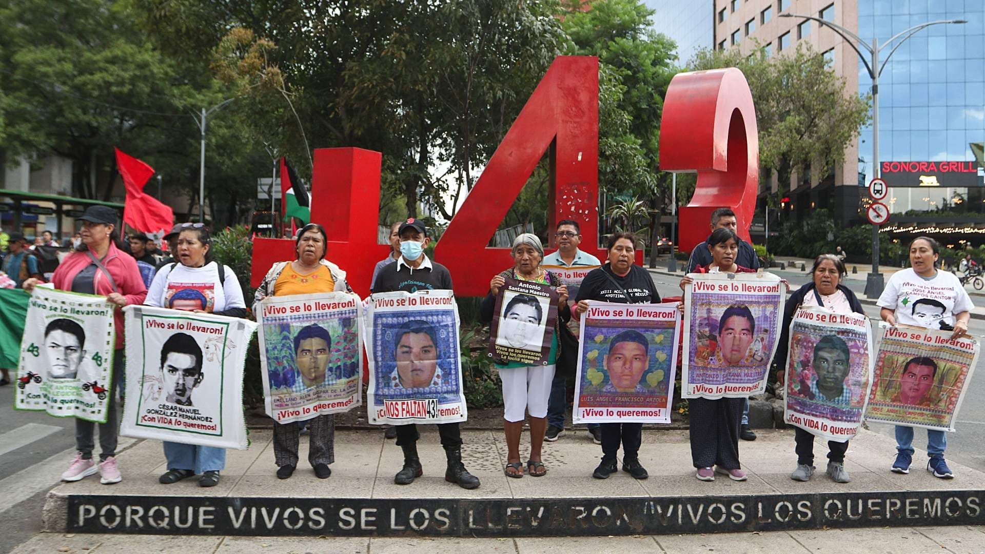 Padres de los estudiantes de Ayotzinapa sostienen carteles con fotos de sus hijos desaparecidos, durante marcha en CDMX en julio 2026