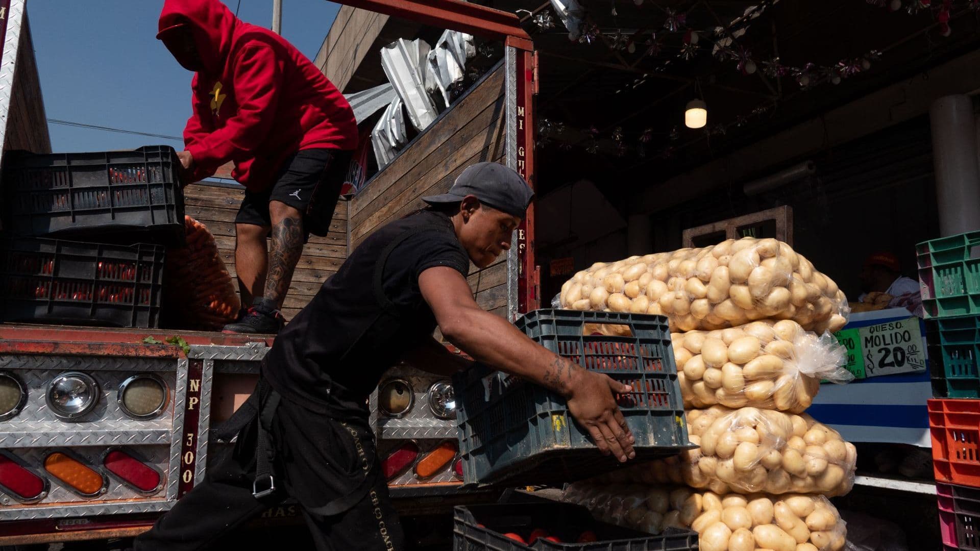 Trabajadores transportan verduras en el Mercado de la Merced.