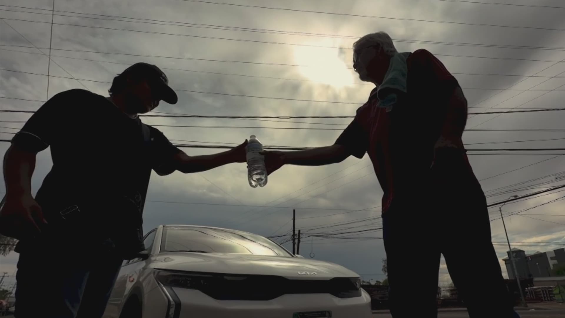 Un hombre otorga una botella de agua a otra persona en Mexicali.
