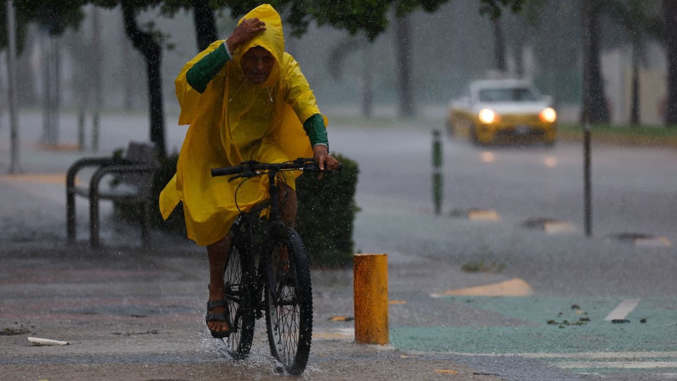 Un hombre conduce su bicicleta en medio de las lluvias provocadas por Simon en Manzanillo, Colima