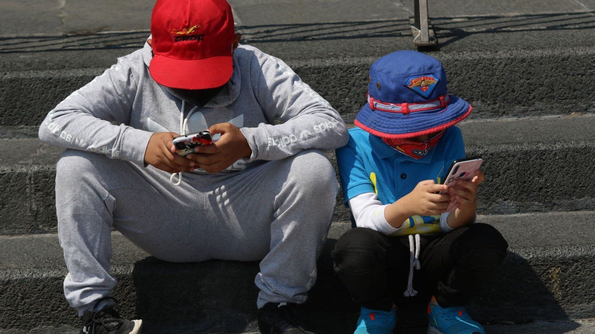 Un par de niños se entretienen con sus respectivos celulares