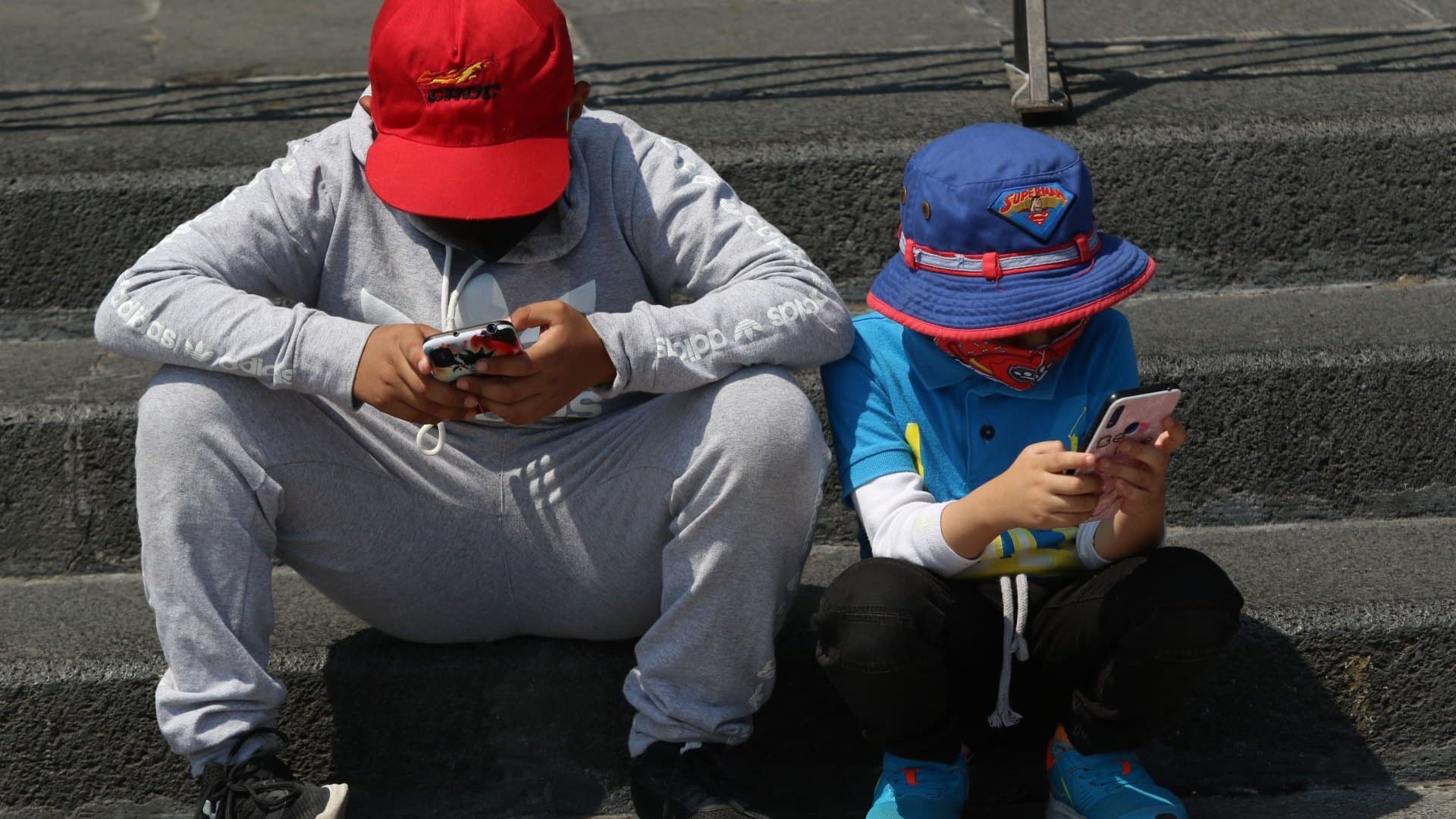 Un par de niños se entretienen con sus respectivos celulares