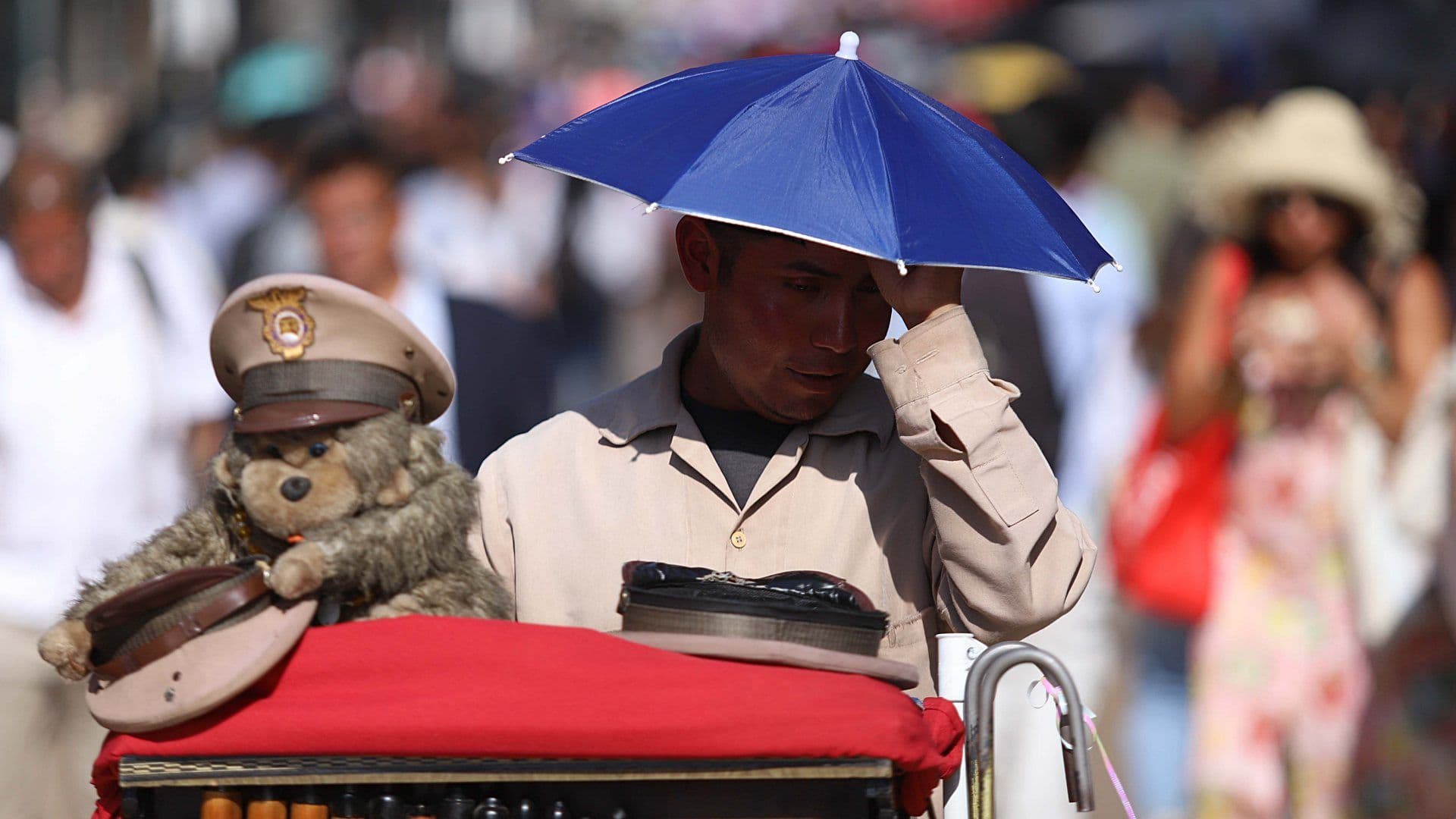 Un organillero se cubre de los rayos del sol con una gorra de sombrilla por ola de calor en CDMX, en abril 2026. Foto: Cuartoscuro | Archivo