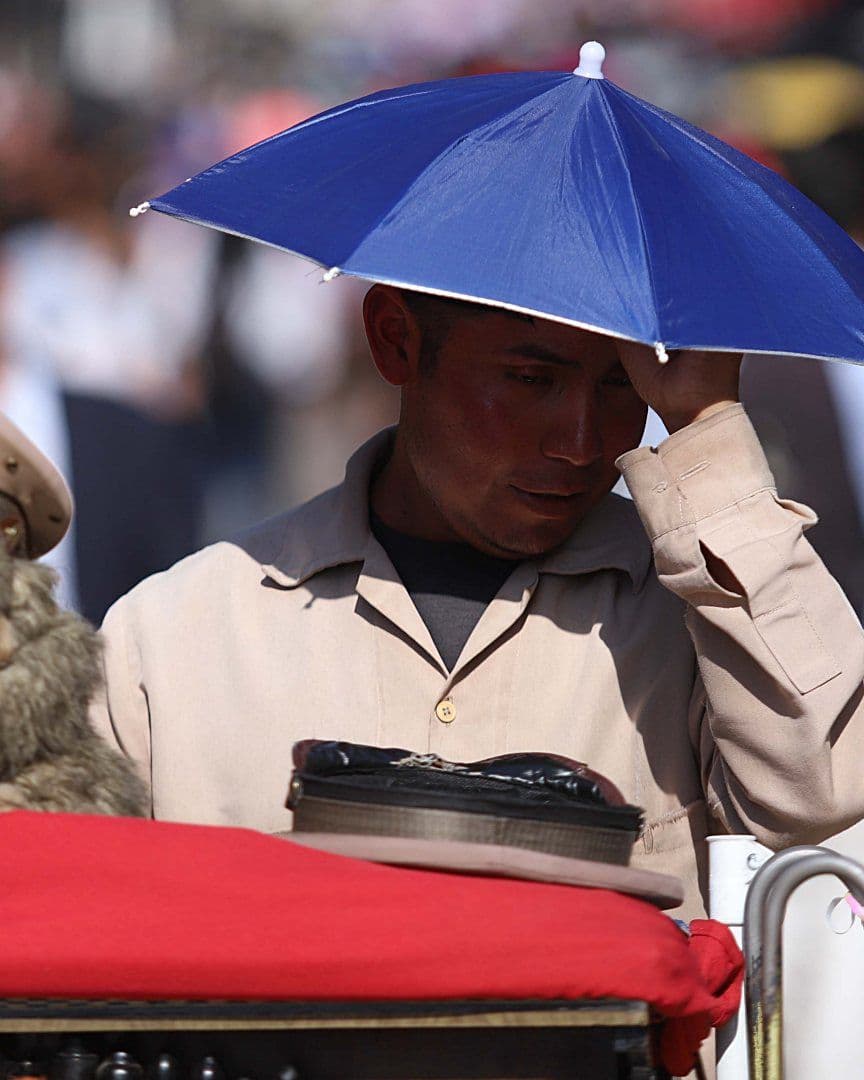 Un organillero se cubre de los rayos del sol con una gorra de sombrilla por ola de calor en CDMX, en abril 2026. Foto: Cuartoscuro | Archivo