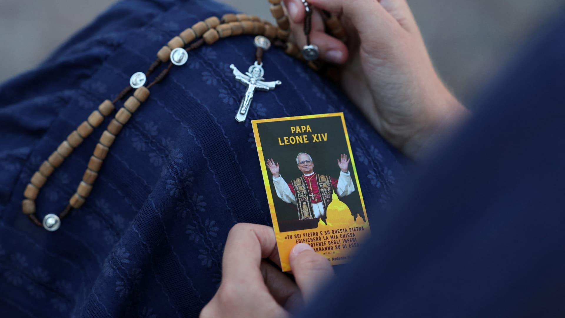 Una mujer sostiene una estampa del papa y un rosario