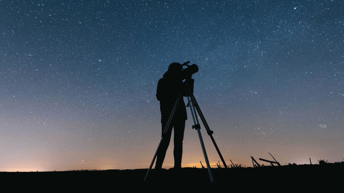 Persona observa el cielo con un telescopio