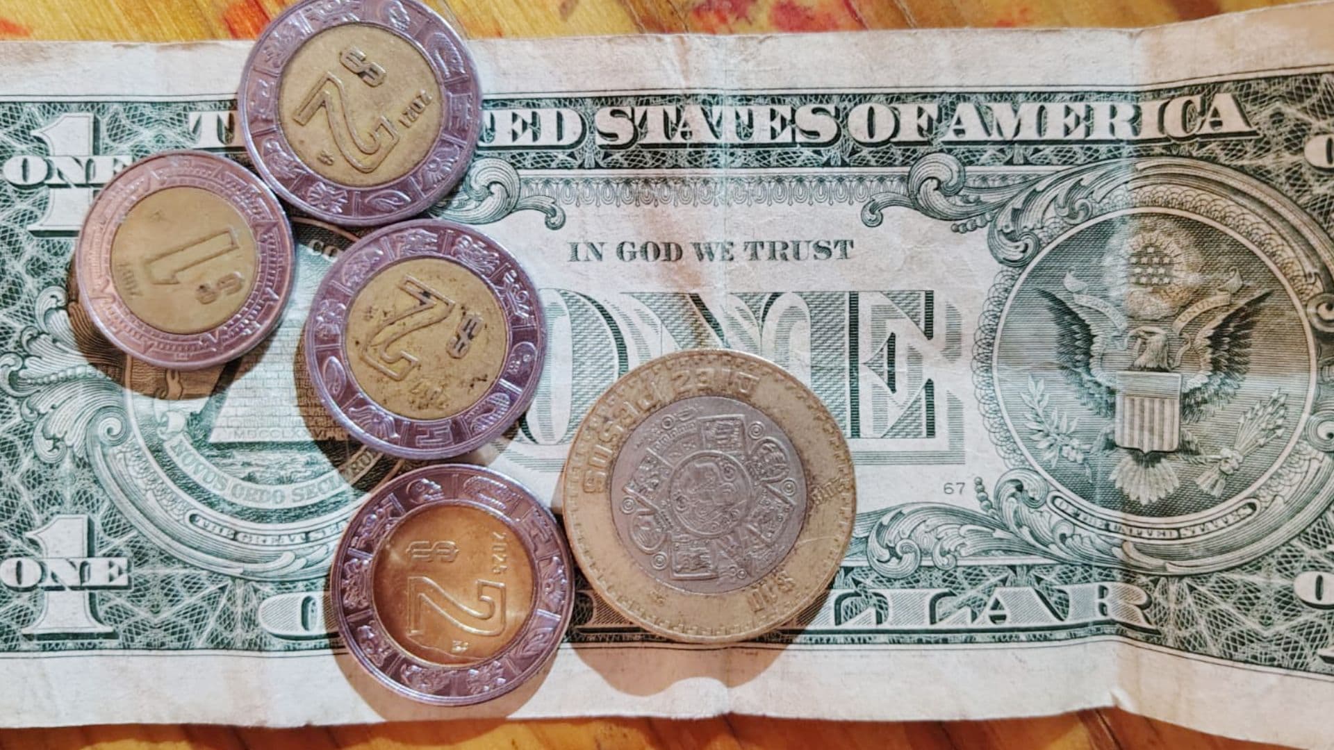 Monedas de pesos mexicanos y un billete de un dólar estadounidense