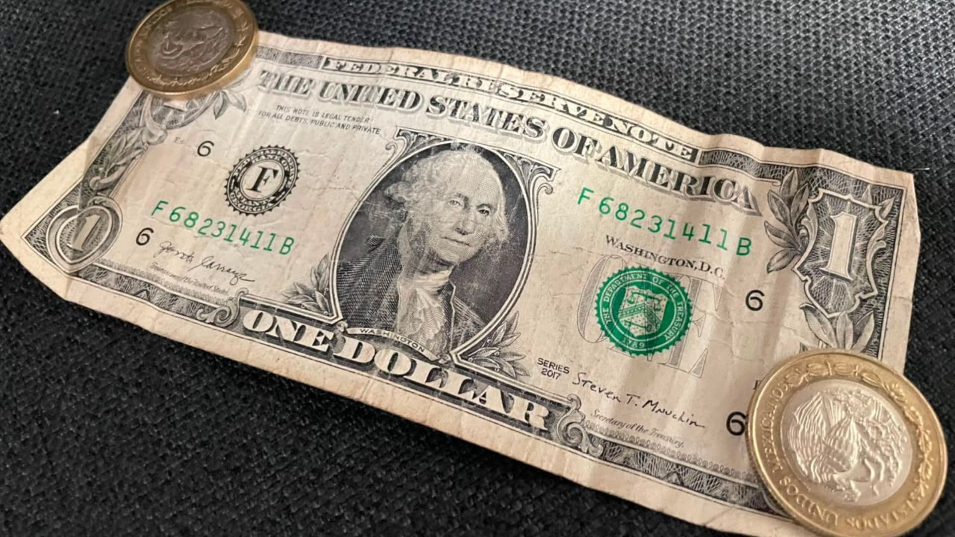 Un billete de un dólar y dos monedas de 10 pesos