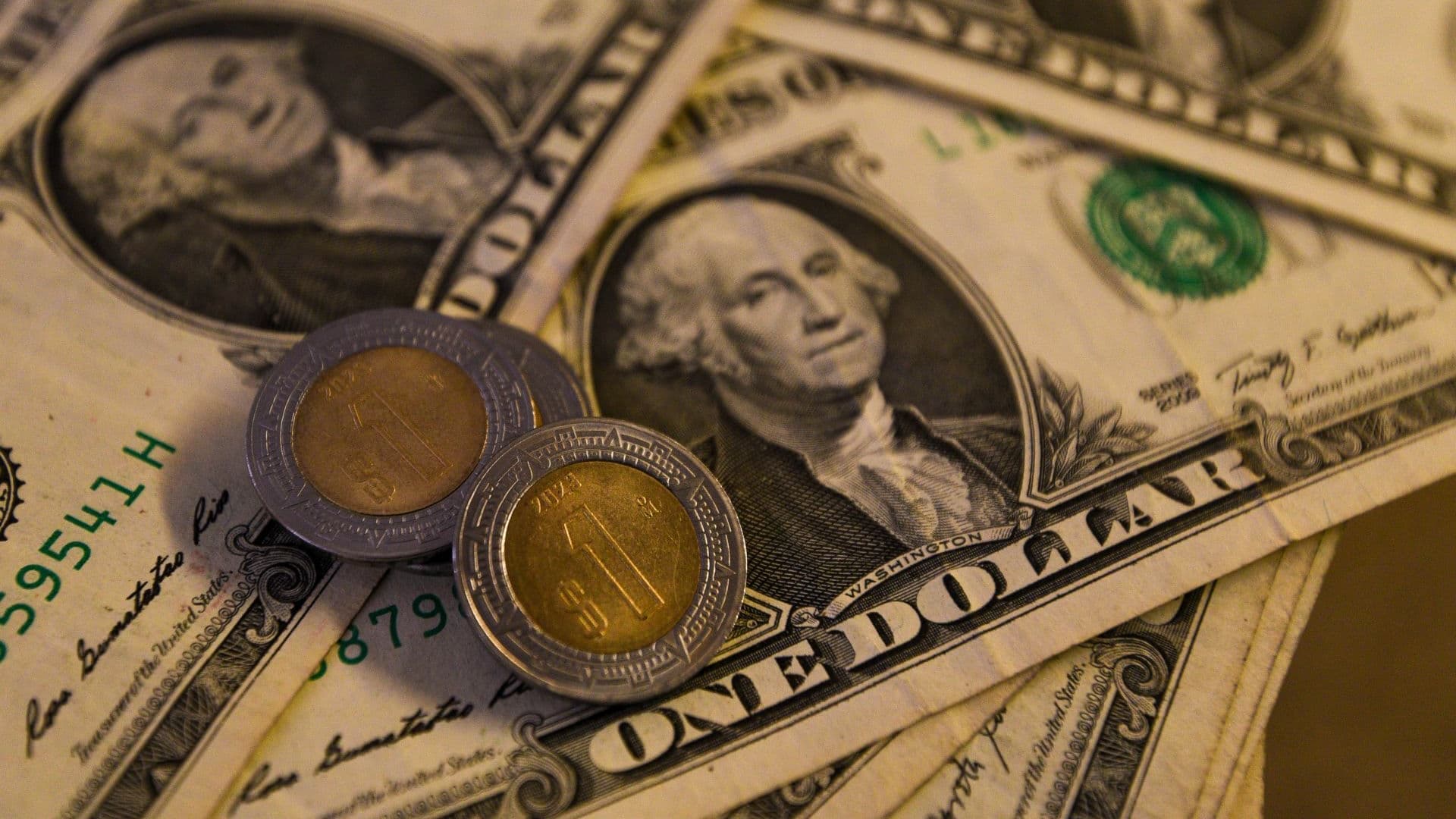 Monedas de un peso mexicano y billete de un dólar estadounidense