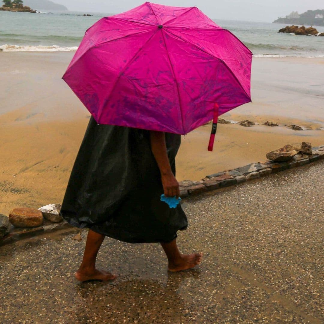 Una mujer camina con una sombrilla una tarde lluviosa en Acapulco