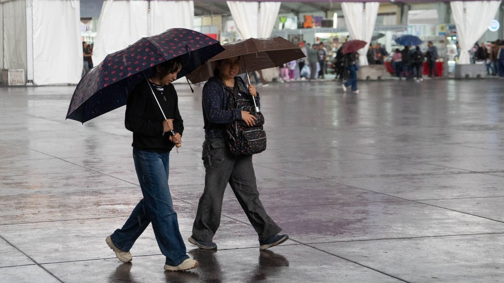 Dos mujeres caminan durante una tarde lluviosa en la zona centro de la CDMX