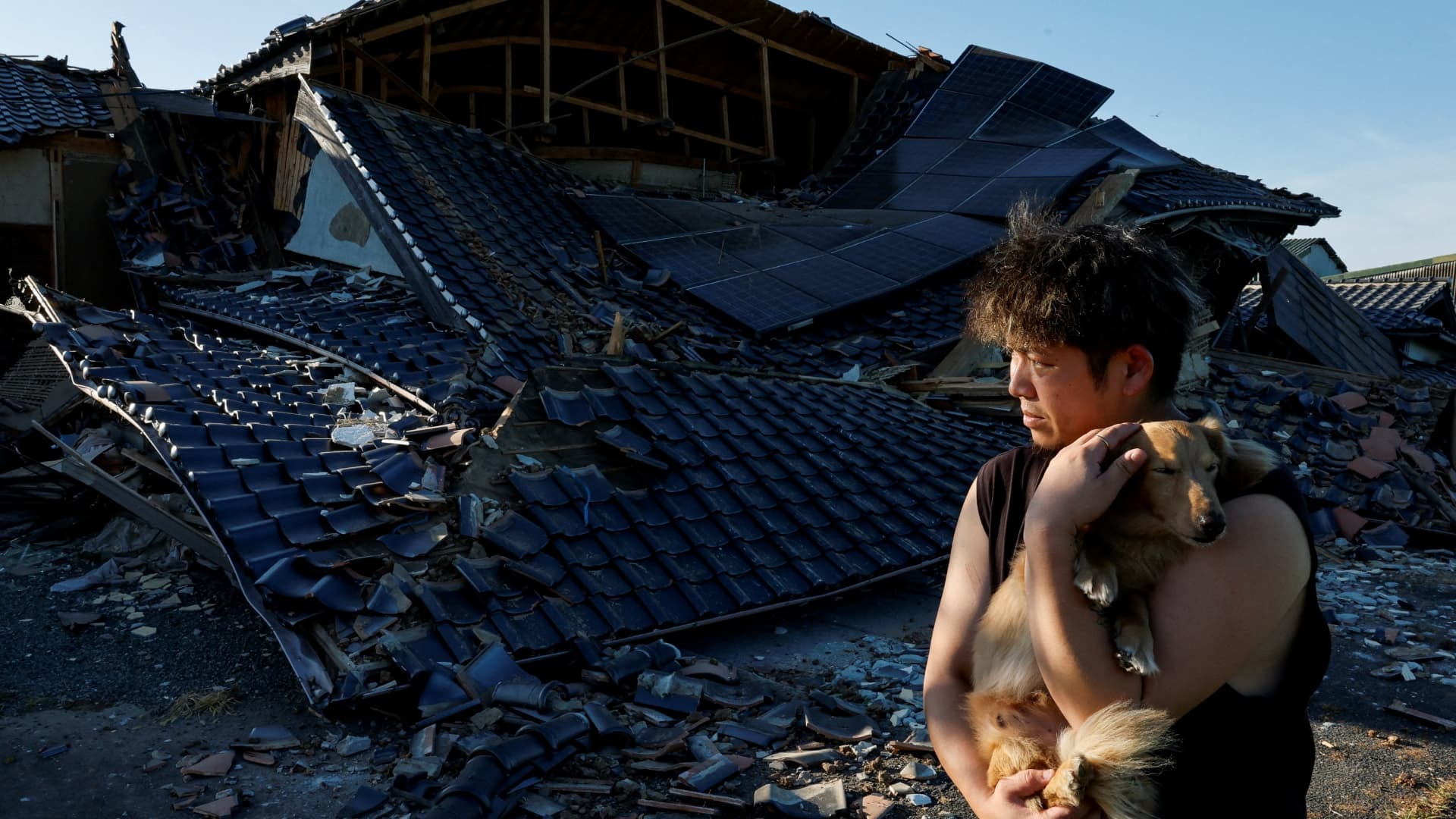 Haruto Kubo, de 26 años, sostiene a su perra Miku frente a la casa donde vive con sus padres, tras el derrumbe del edificio a causa de un terremoto que sacudió la prefectura de Kumamoto. Foto: Reuters