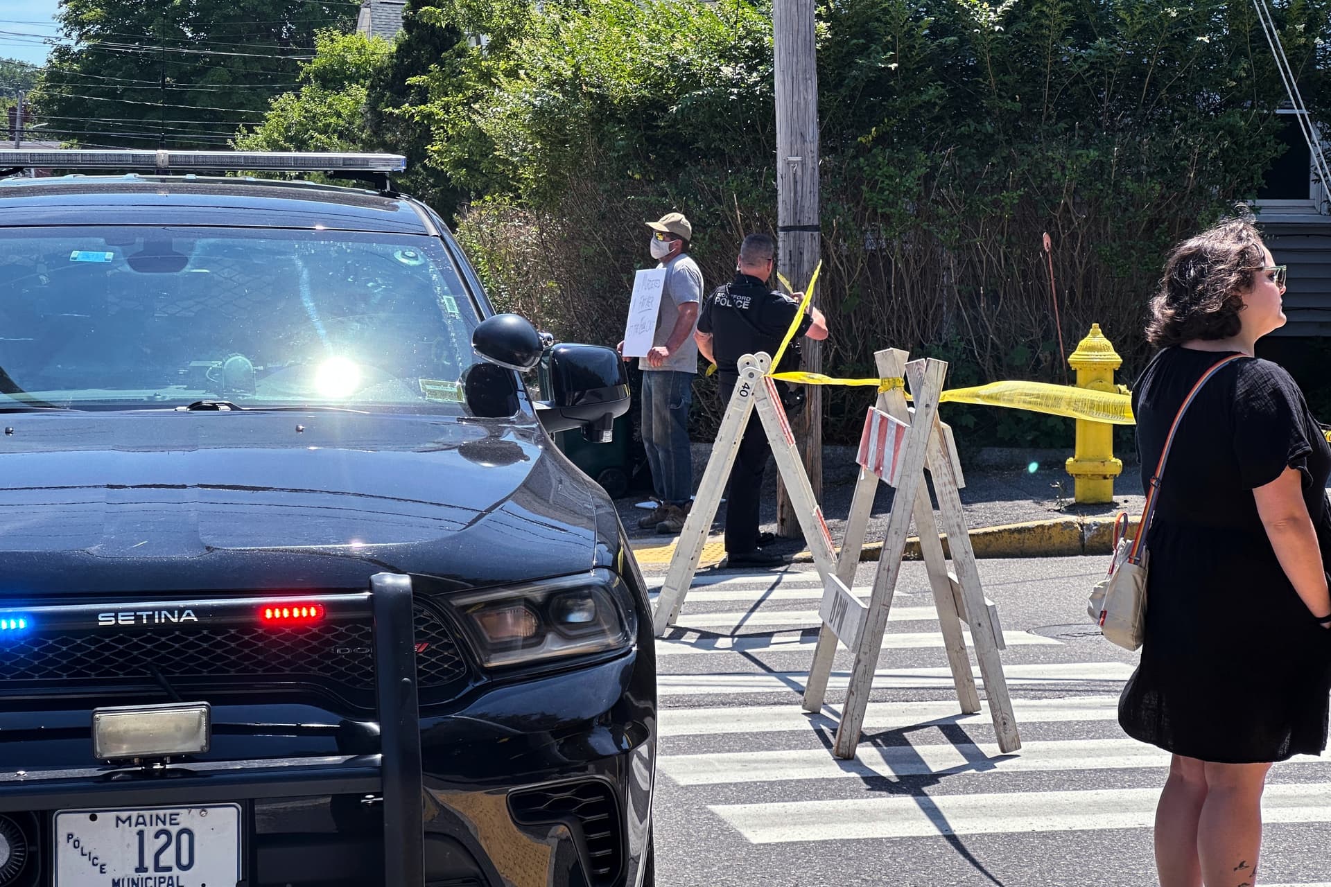 Personas observan el operativo mientras autoridades mantienen cerrada una carretera tras un tiroteo relacionado con agentes del ICE en Biddeford, Maine.