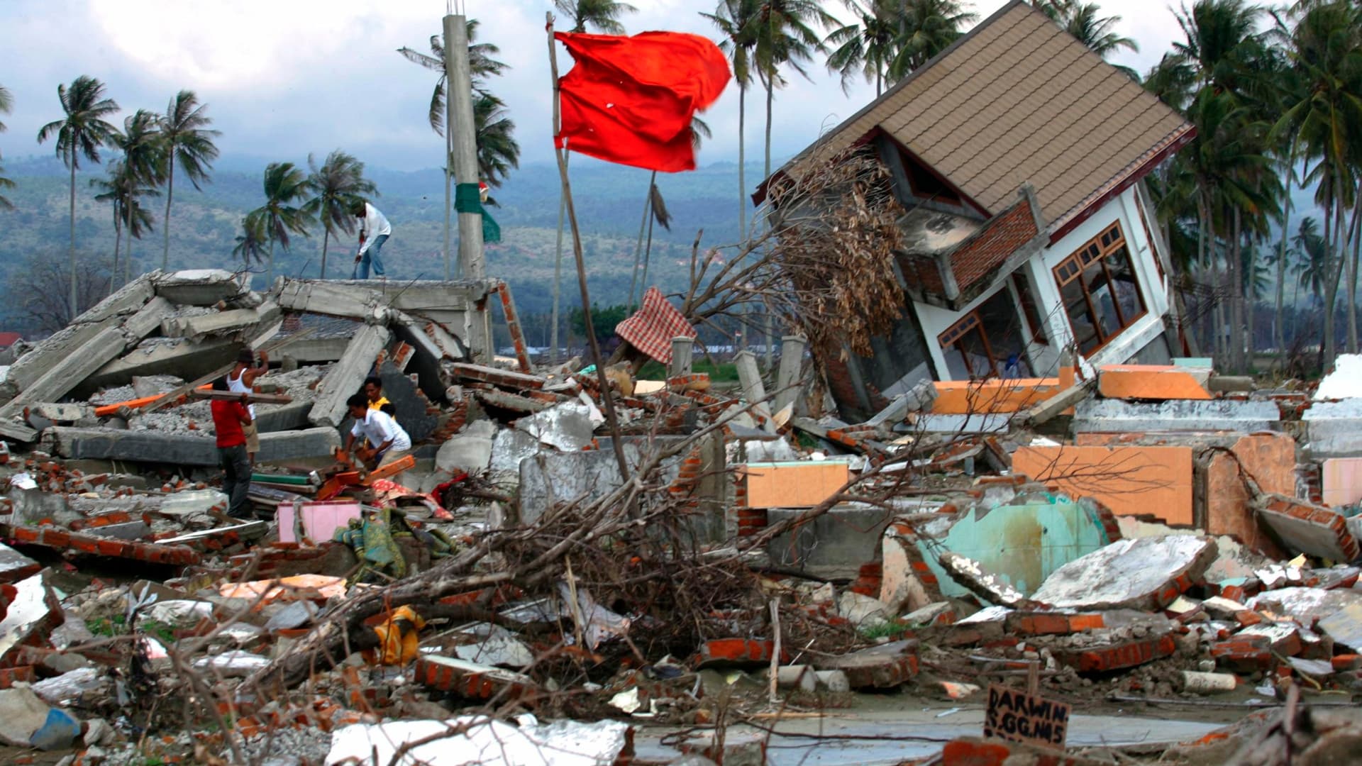 Hombres de Aceh en Indonesia caminan entre los escombros de sus casas devastadas tras el tsunami de 2004. Foto: Reuters