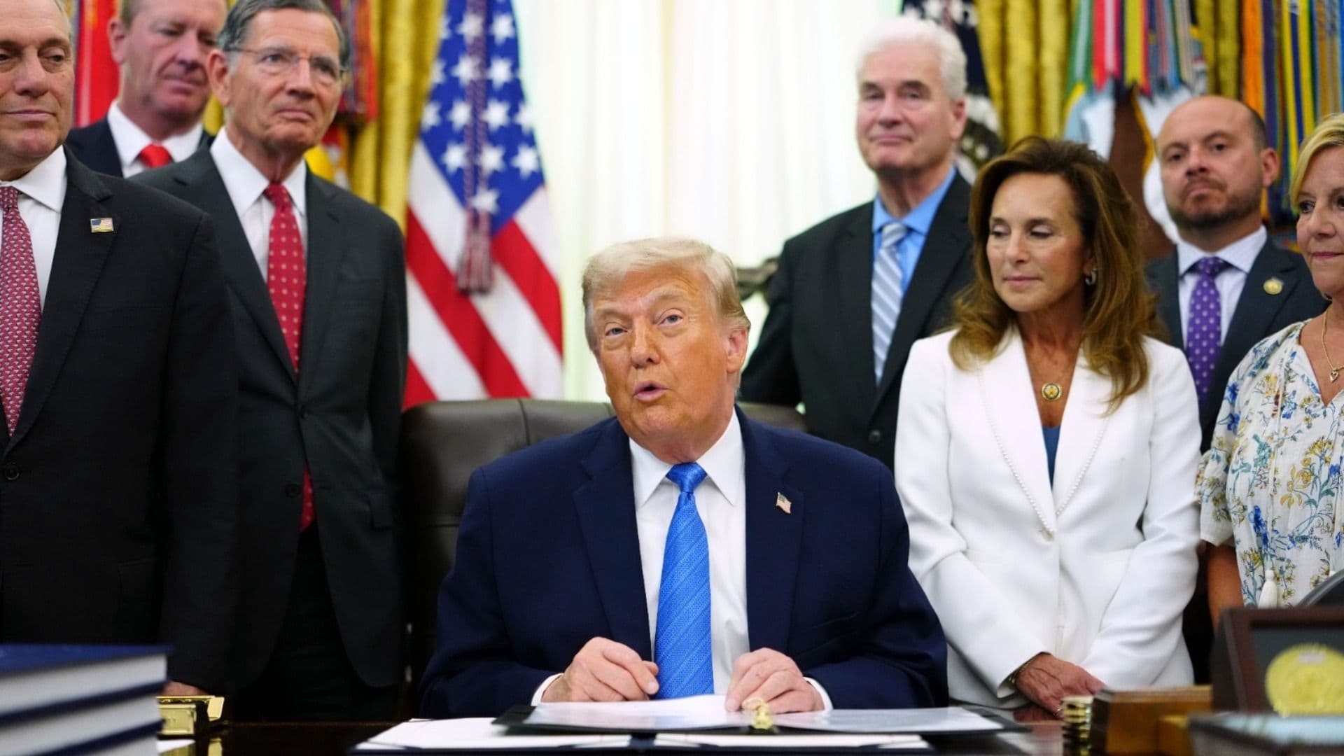 El presidente de Estados Unidos, Donald Trump, muestra la Ley de Seguridad Estadounidense tras firmarla en el Despacho Oval de la Casa Blanca