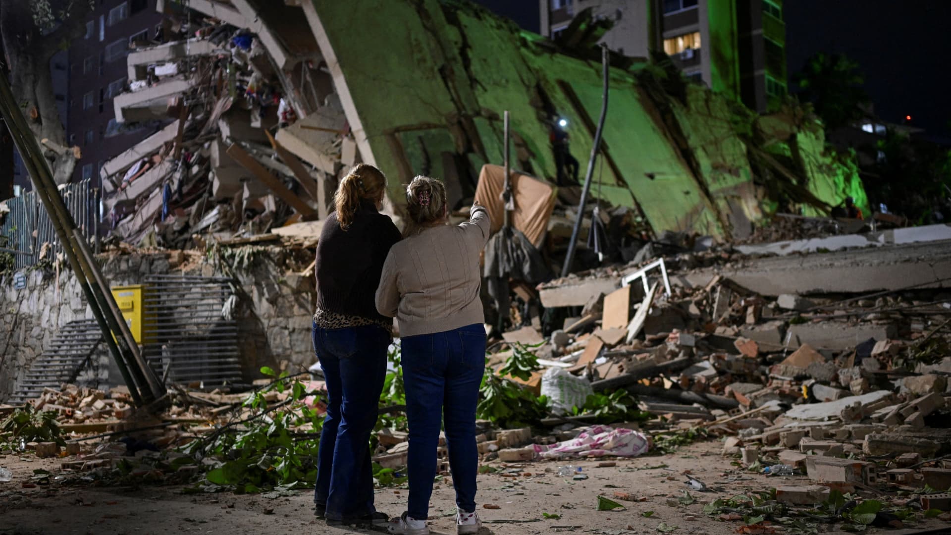 Venezolanas esperan en el lugar de un edificio derrumbado mientras los equipos de emergencia buscan a sus familiares.