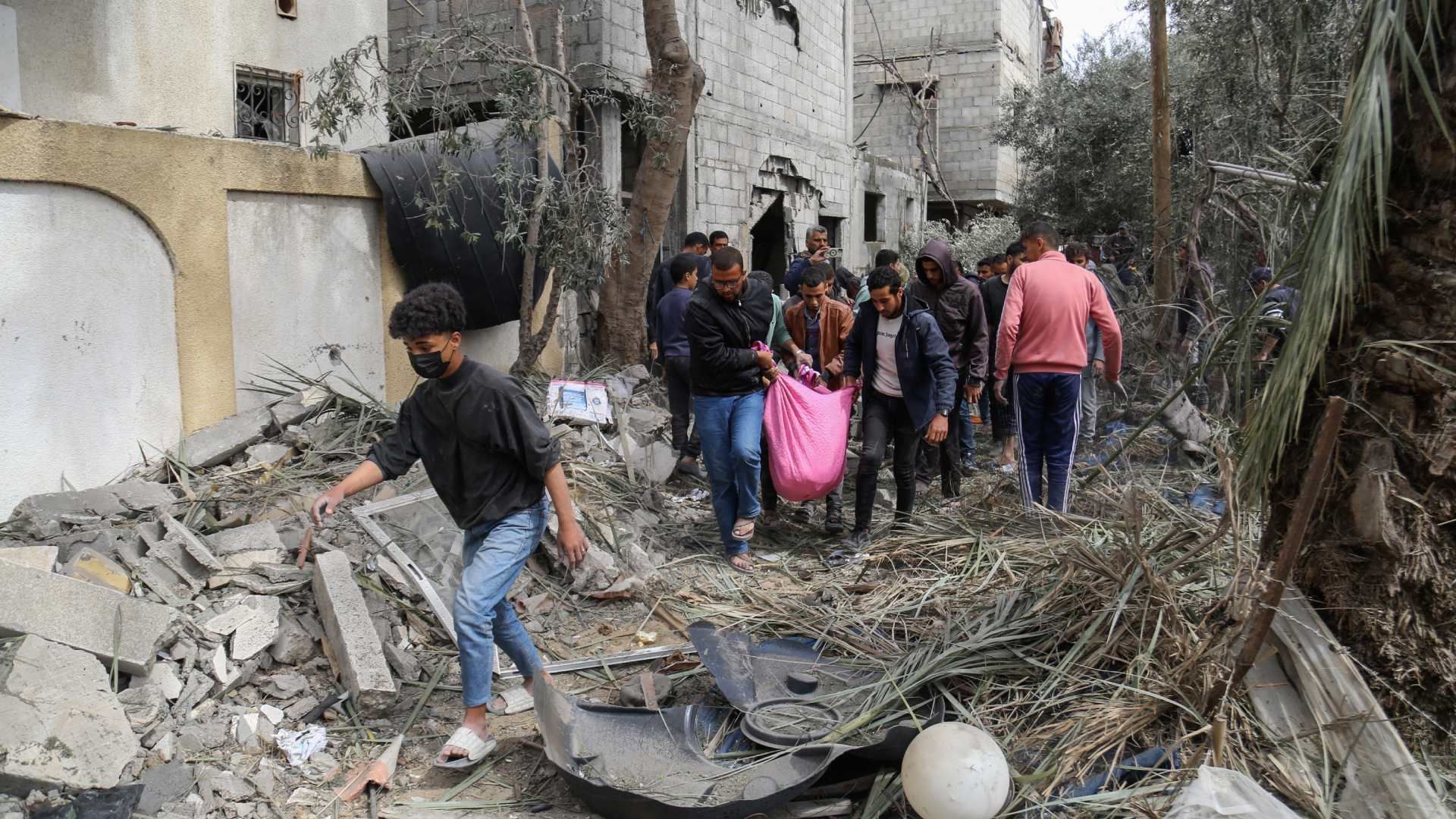 palestinos transportan a una víctima sacada de los escombros de una casa familiar tras el bombardeo israelí