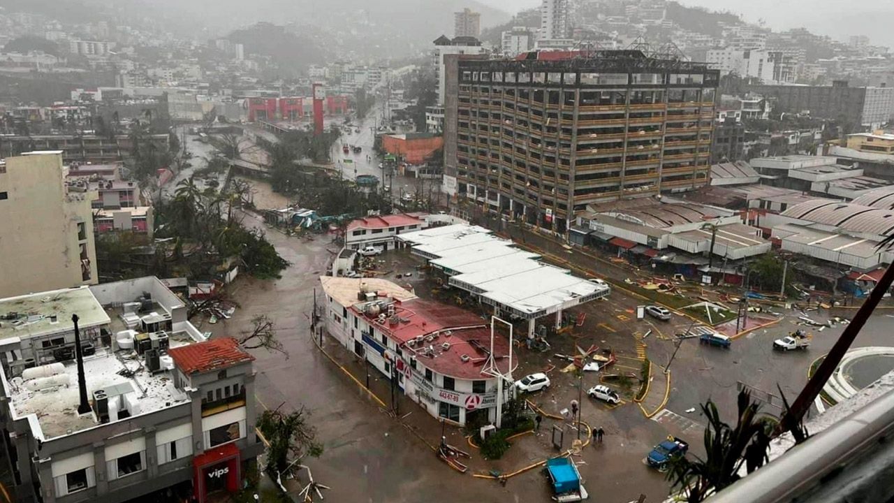 Acapulco inundado: edificios dañados, vehículos dispersos, árboles caídos y calles desoladas.