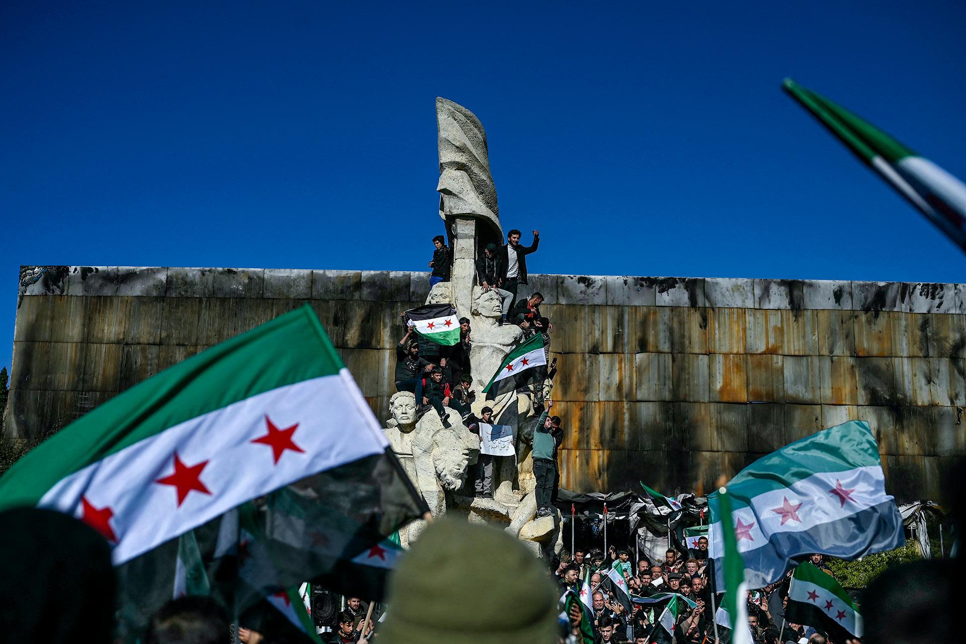 Personas ondean banderas de la revolución siria en la plaza Saadallah al-Jabiri para celebrar el derrocamiento del presidente Bashar al-Assad