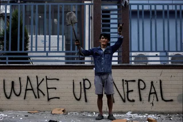Manifestante tras una protesta en Katmandú; detrás una pinta reza ‘Despierta, Nepal’