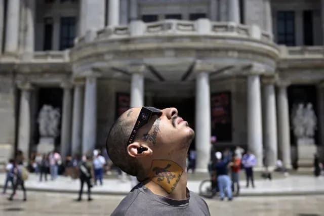 Hombre admira el eclipse frente al Palacio de Bellas Artes
